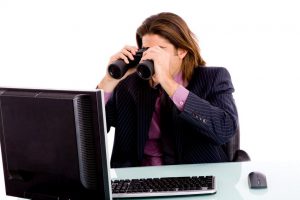 Oklahoma businesswoman looking at computer through binoculars